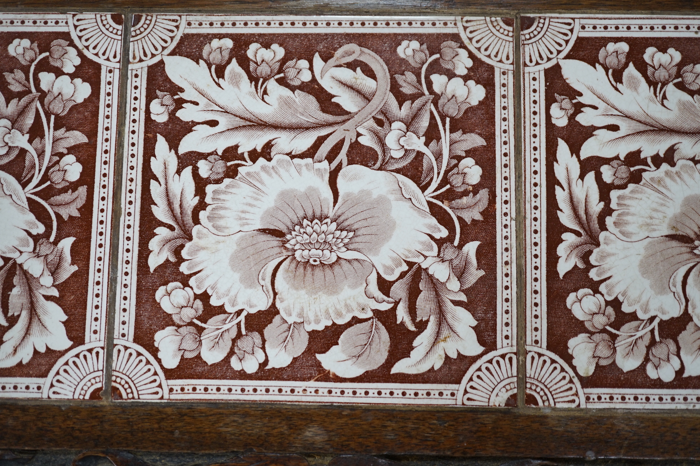 A Victorian carved oak stand inset with there floral tiles, 69cm wide